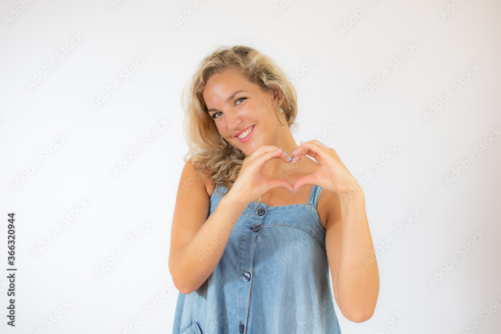 Pretty blonde woman in blue dress smiling making the heart figure Pretty blonde woman in blue dress smiling making the heart figure