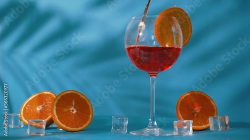 Cold refreshing drink with oranges on a blue background with ice