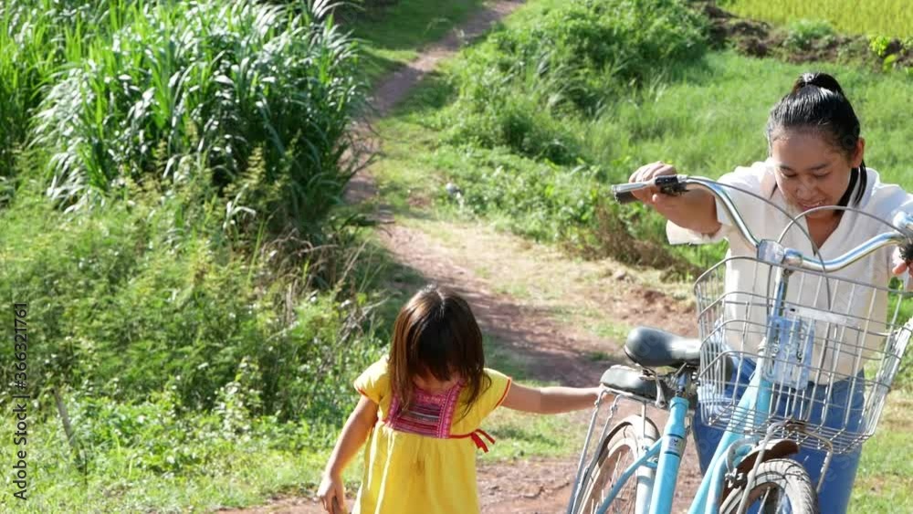 Young mother and her daughter walking with bicycle on summer park outdoors. Relaxation and lifestyle in vacation. Young mother and her daughter walking with bicycle on summer park outdoors. Relaxation and lifestyle in vacation.