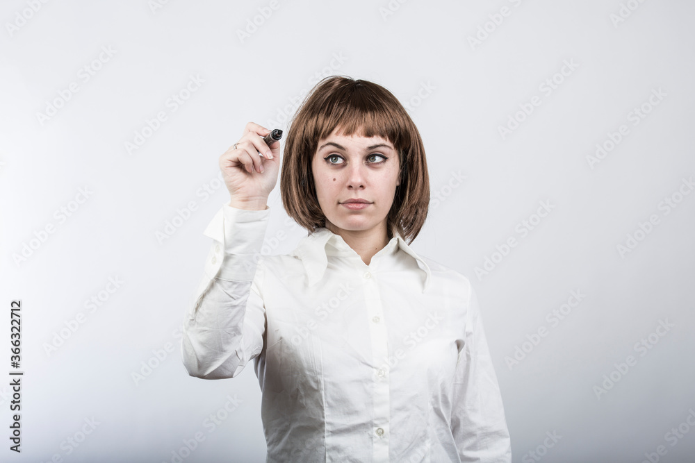 Ragazza chiara con capelli a caschetto e camicia bianca scrive qualcosa con un pennarello in un ipotetica parete trasparente, isolata su sfondo bianco Ragazza chiara con capelli a caschetto e camicia bianca scrive qualcosa con un pennarello in un ipotetica parete trasparente, isolata su sfondo bianco