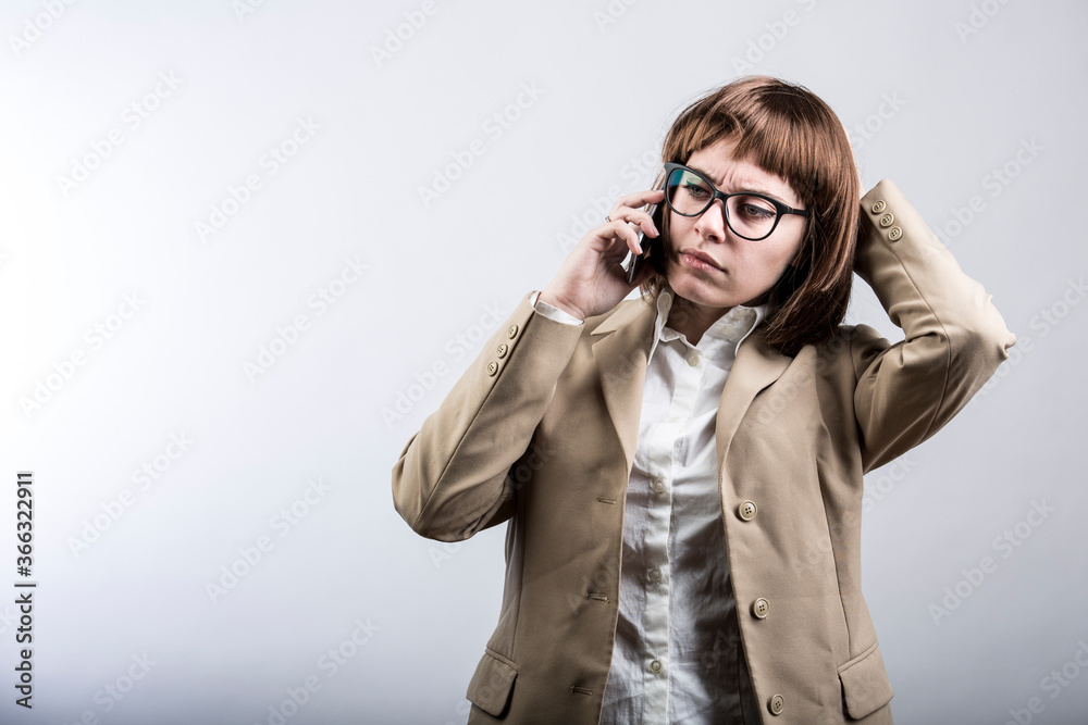 ragazza con capelli a caschetto castani , occhiali e giacca beige utilizza il suo smartphone per mettersi in contatto con un altra persona, isolata su sfondo bianco ragazza con capelli a caschetto castani , occhiali e giacca beige utilizza il suo smartphone per mettersi in contatto con un altra persona, isolata su sfondo bianco