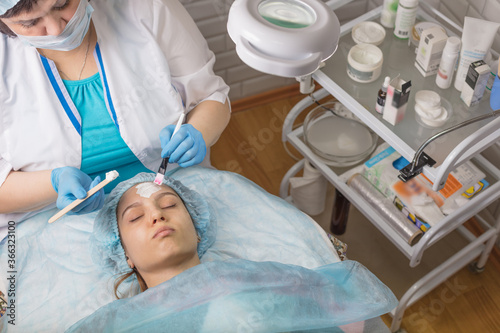 A young girl is cleaning the skin of her face at a cosmetologist. Facial cleansing and massage