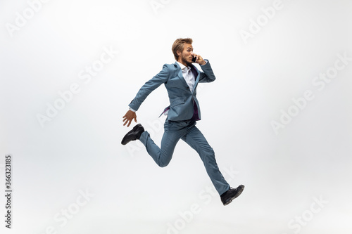 Deals. Man in office clothes running, jogging on white background like professional athlete, sportsman. Unusual look for businessman in motion, action with ball. Sport, healthy lifestyle, creativity.
