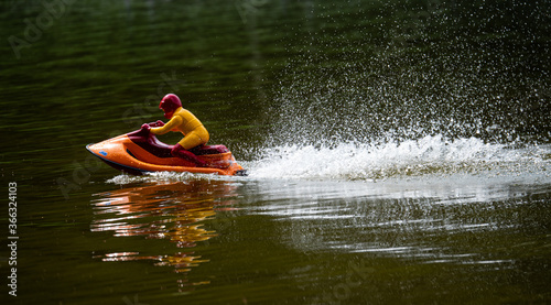 RC controlled jet ski model on lake.