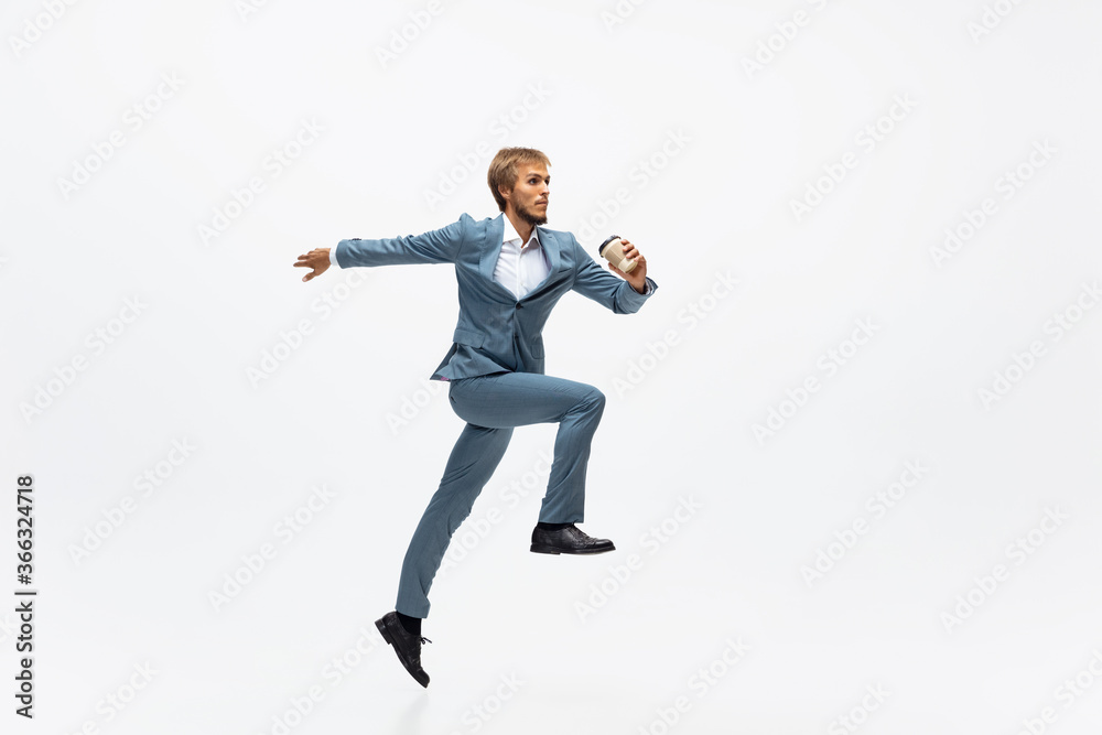 Coffee time. Man in office clothes running, jogging on white background like professional athlete, sportsman. Unusual look for businessman in motion, action with ball. Sport, healthy lifestyle Coffee time. Man in office clothes running, jogging on white background like professional athlete, sportsman. Unusual look for businessman in motion, action with ball. Sport, healthy lifestyle