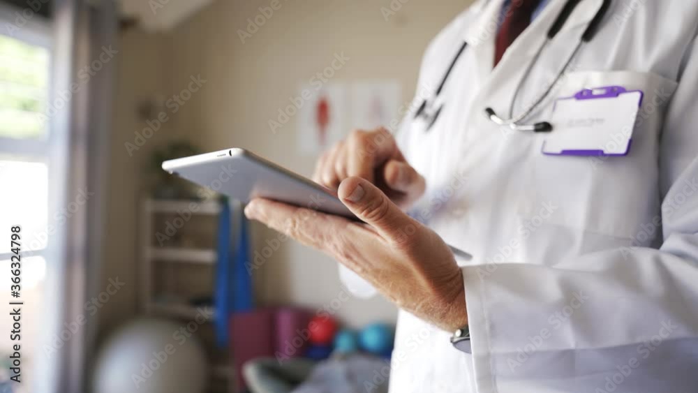 Caucasian doctor in surgeon coat on digital tablet capturing medical data