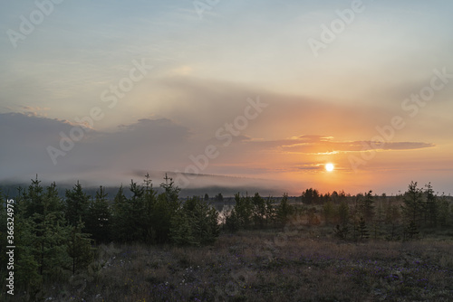 Rising sun among clouds and fog