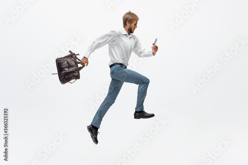 Chatting on the go. Man in office clothes running, jogging on white background like professional athlete, sportsman. Unusual look for businessman in motion, action with ball. Sport, healthy lifestyle