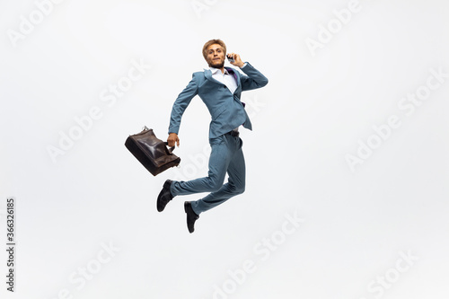 Successful. Man in office clothes running, jogging on white background like professional athlete, sportsman. Unusual look for businessman in motion, action with ball. Sport, healthy lifestyle © master1305