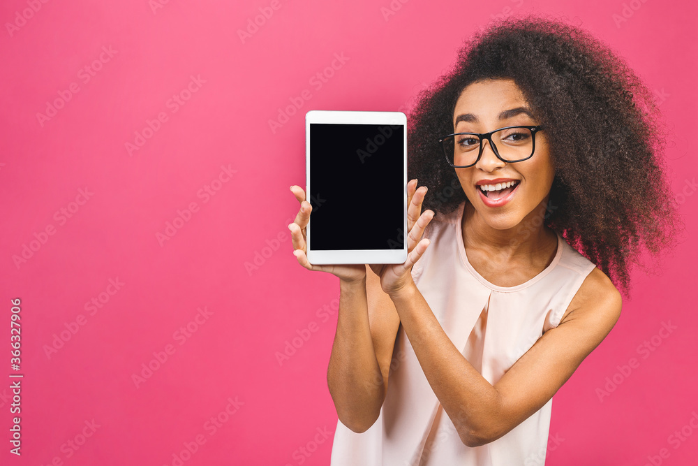 Smiling afro american young student woman showing blank tablet computer isolated over pink background.