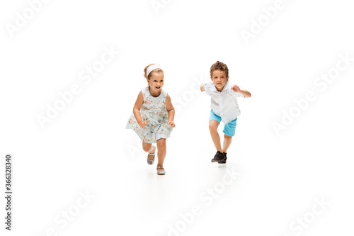 Happy children  little and emotional caucasian boy and girl jumping and running isolated on white background. Look happy  cheerful  sincere. Copyspace for ad. Childhood  education  happiness concept.