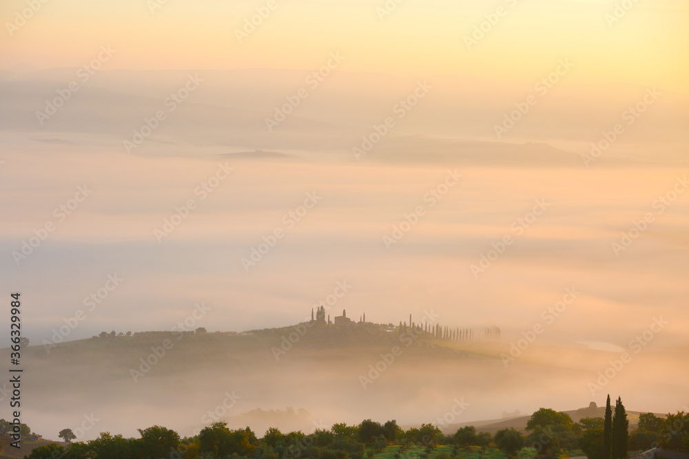 Picturesque view of foggy rolling fields of Tuscany in the light of the rising sun, Val d'Orcia, Italy.