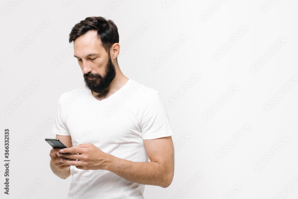 Pensive young man is using a mobile phone. space for text Pensive young man is using a mobile phone. space for text