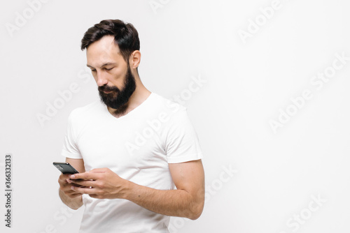  Pensive young man is using a mobile phone. space for text © Yuliya