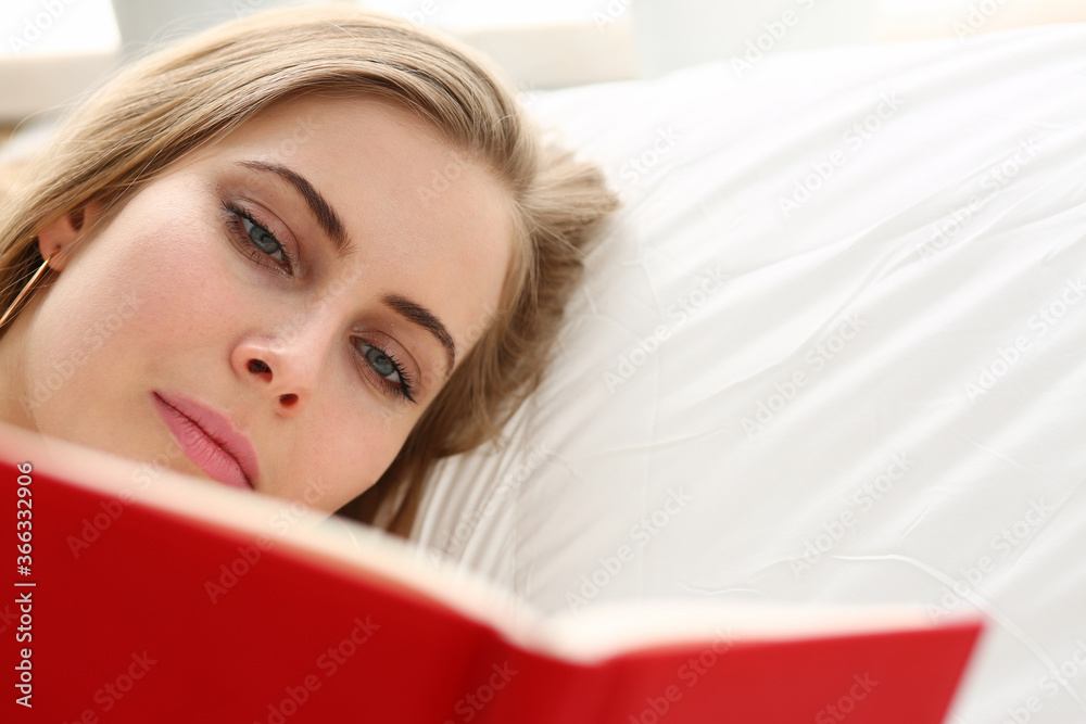 Relaxed young female person enjoying her weekend and lying in bed with her favorite book Relaxed young female person enjoying her weekend and lying in bed with her favorite book