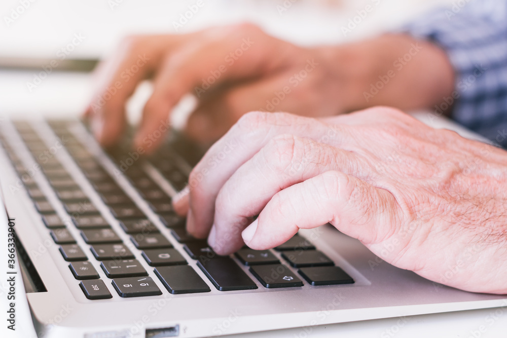 Older person's hands typing on a gray laptop. Older person's hands typing on a gray laptop.