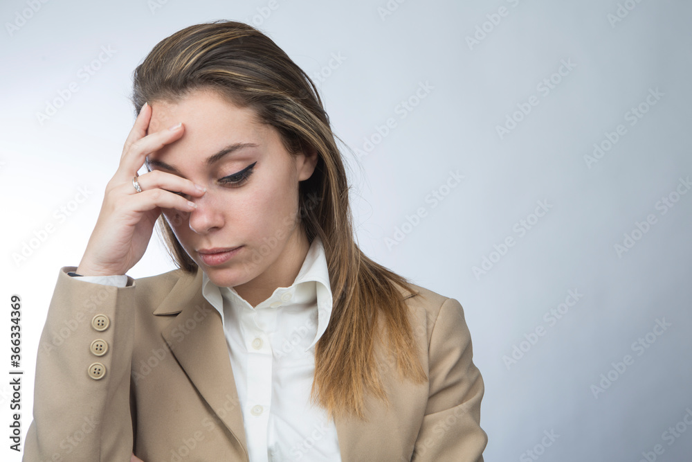 Manager donna bionda in giacca beige si porta la mano alla fronte e guarda in basso con espressione depressa, isolata su sfondo bianco Manager donna bionda in giacca beige si porta la mano alla fronte e guarda in basso con espressione depressa, isolata su sfondo bianco