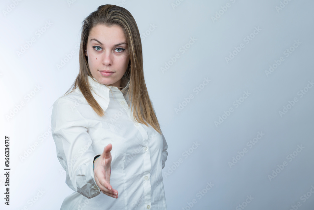 ragazza bionda con camicia bianca fa il segno di dare la mano , isolata su sfondo chiaro ragazza bionda con camicia bianca fa il segno di dare la mano , isolata su sfondo chiaro