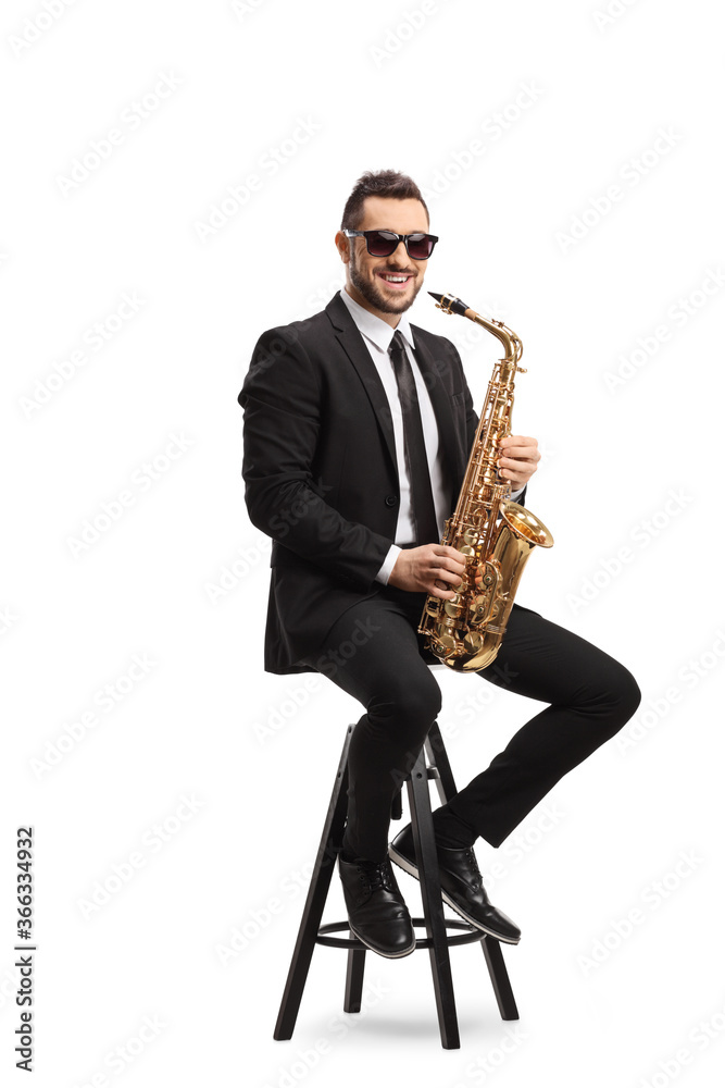 Naklejka premium Man sitting on a chair with a saxophone and smiling at the camera