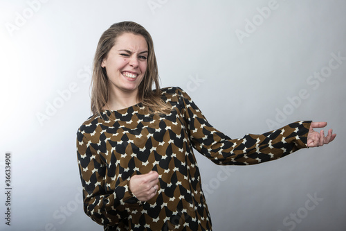 ragazza divertente con maglia fantasia balla e finge di suonare uno strumento musicale  isolata su sfondo bianco photo