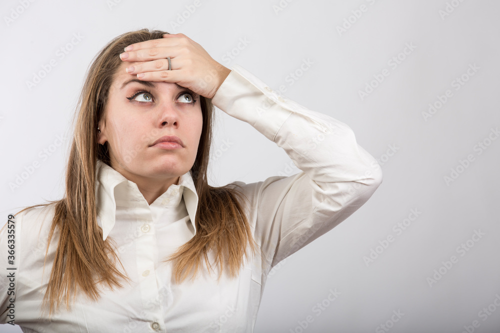 ragazza bionda con camicia bianca si porta le mani alla fronte per sentire la temperatura e capire se avesse la febbre, isolata su sfondo bianco ragazza bionda con camicia bianca si porta le mani alla fronte per sentire la temperatura e capire se avesse la febbre, isolata su sfondo bianco