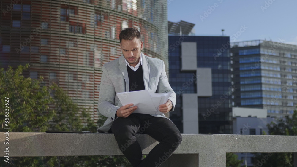 Fototapeta premium Businessman looking graphs on documents at street. Entrepreneur going for work