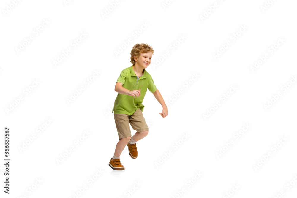 Fototapeta premium Happy child, little and emotional caucasian boy jumping and running isolated on white background. Looks happy, cheerful, sincere. Copyspace for ad. Childhood, education, happiness concept.
