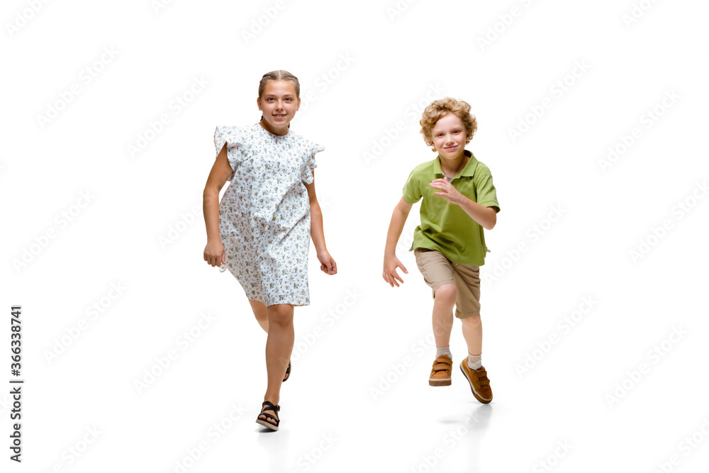Happy children, little and emotional caucasian girl and boy jumping and running isolated on white background. Looks happy, cheerful, sincere. Copyspace for ad. Childhood, education, happiness concept. Happy children, little and emotional caucasian girl and boy jumping and running isolated on white background. Looks happy, cheerful, sincere. Copyspace for ad. Childhood, education, happiness concept.