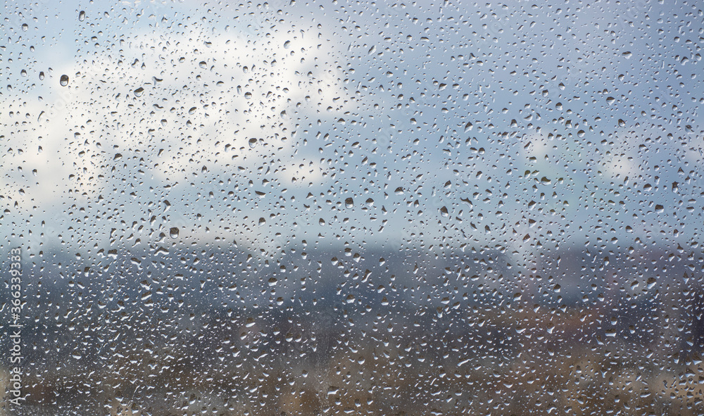 Drops on the window after the rain on the background of the city and the blue sky. Soft focus. Blurs.