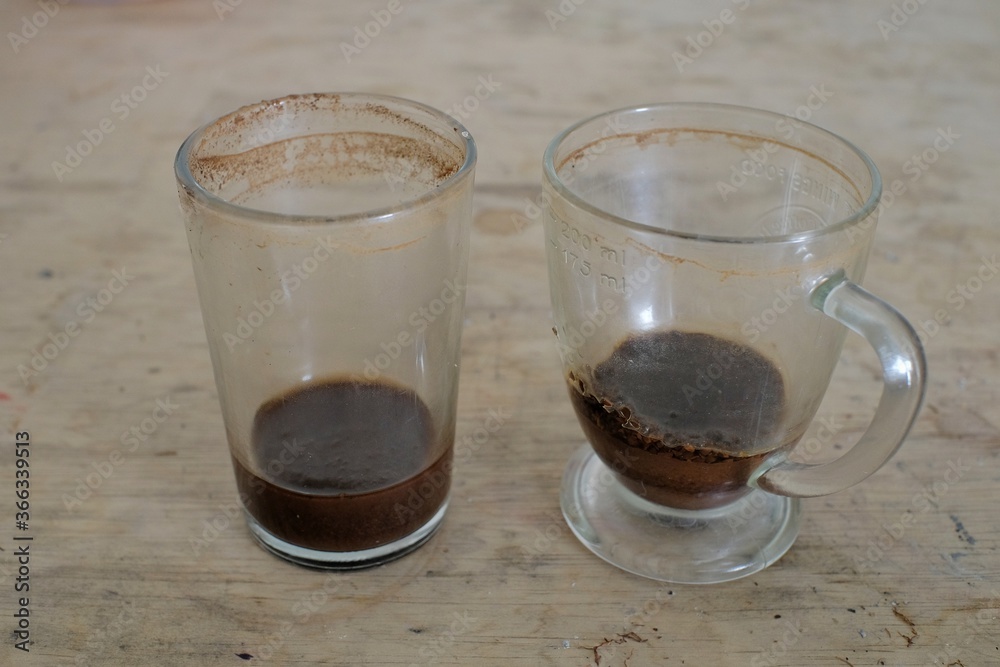 Two dirty glasses with the remaining coffee grounds remain at the bottom Two dirty glasses with the remaining coffee grounds remain at the bottom