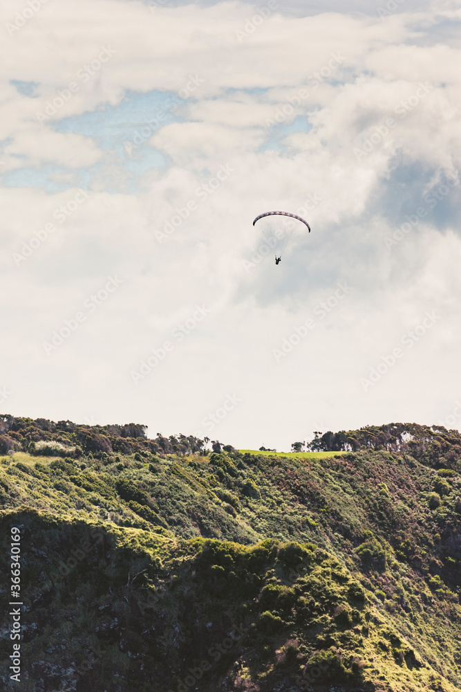 Paraglider over hills of Bay of Islands, New Zealand Paraglider over hills of Bay of Islands, New Zealand