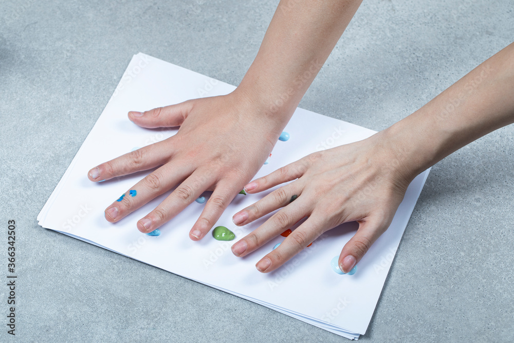A kid marking his handprint on bank paper with colors A kid marking his handprint on bank paper with colors