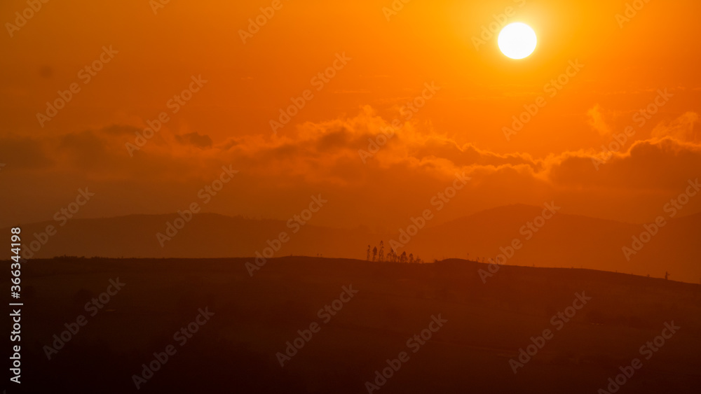 sunset between clouds and mountains in summer sunset between clouds and mountains in summer