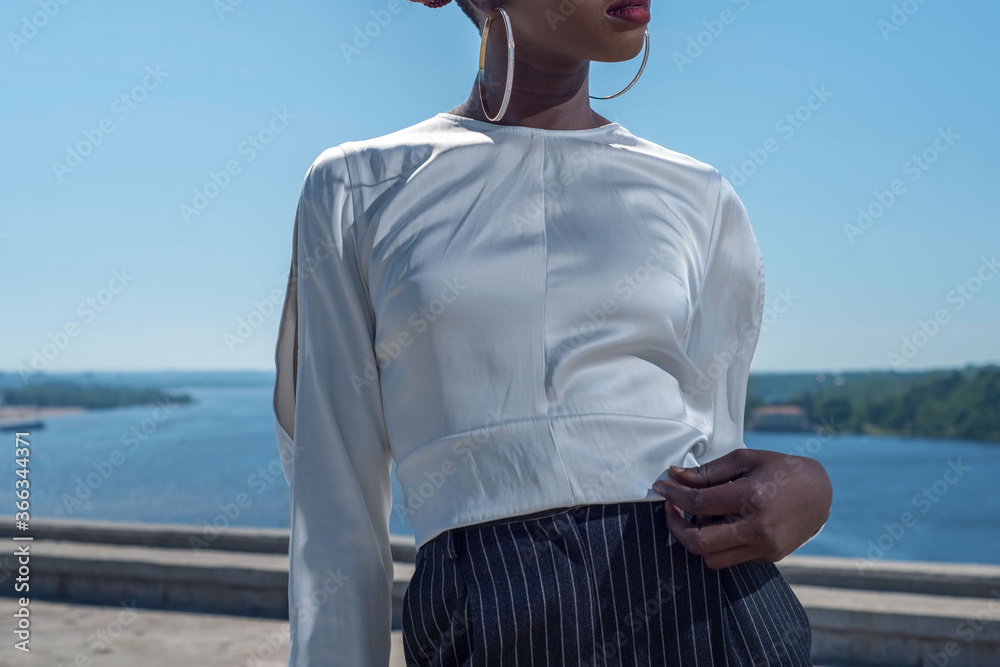 young african black model posing showing details of a white blouse. Fashionable shot against a blue sky young african black model posing showing details of a white blouse. Fashionable shot against a blue sky