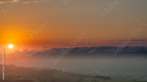 sunset between clouds and mountains in summer