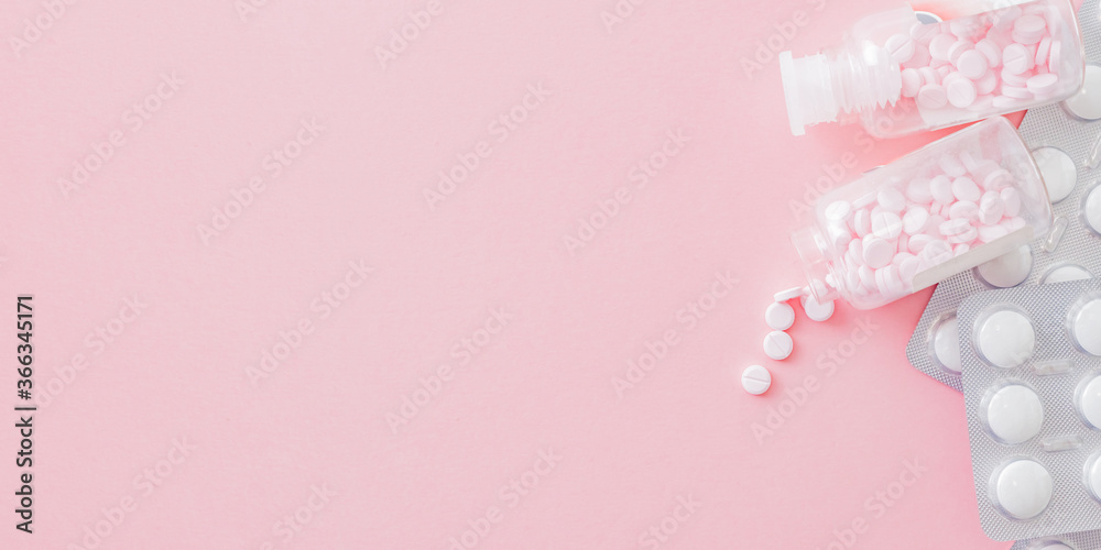 White pills in a blister and pink pills in a bottle on a pink background. Medical pharmacy concept