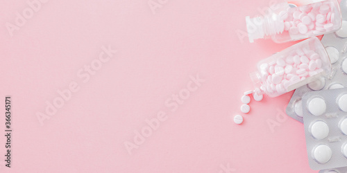 White pills in a blister and pink pills in a bottle on a pink background. Medical pharmacy concept © maria_lh