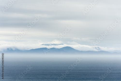 Distant cloudy hills of New Zealand s South Island seen over Cook Strait