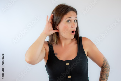 Beautiful young woman in black shirt making listening gesture