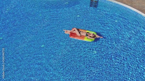 beautiful girl in a swimsuit floating in the pool, on a hot summer day