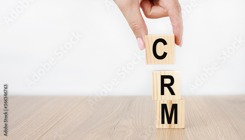 Concept word 'CRM' on cubes on a beautiful wooden table. White background. Business concept. Copy space.