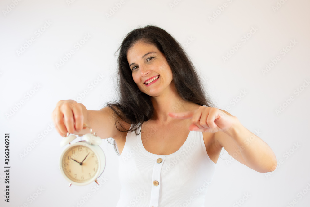 Pretty young woman with long black hair pointing at clock Pretty young woman with long black hair pointing at clock