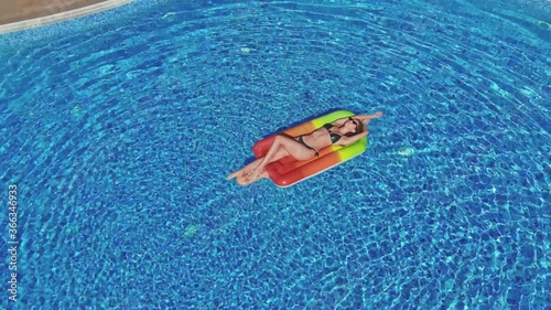 beautiful girl in a swimsuit floating in the pool, on a hot summer day