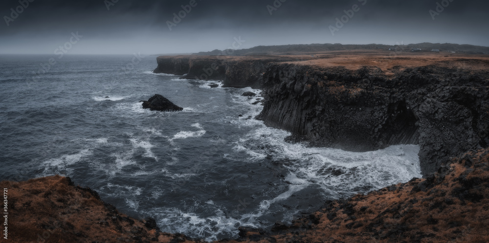 Western Iceland nature landscape, panorama view. Basalt rock cliff in Snaefellsnes (Snæfellsnes) peninsula near Arnarstapi village. Stormy waves at rainy weather