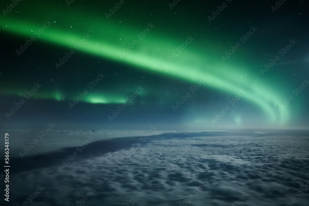 Northern lights or Aurora Borealis above the clouds, view from plane. Night sky landscape