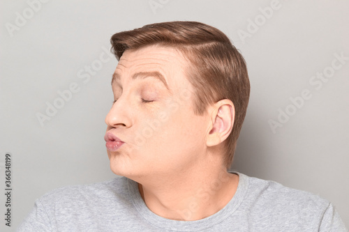 Portrait of funny mature man pouting his lips and blowing kiss