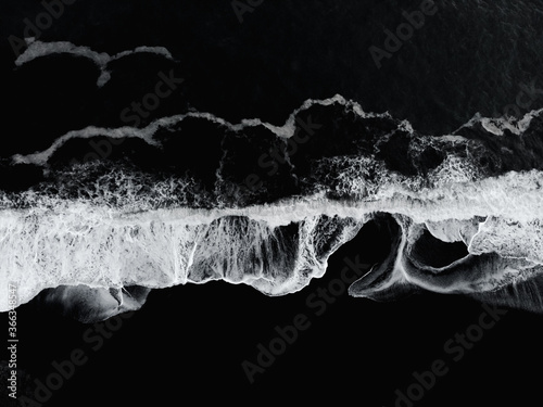 Aerial drone view of Reynisfjara Black Sand Beach and ocean waves in South Iceland near Vik village at sunset. Abstract nature background