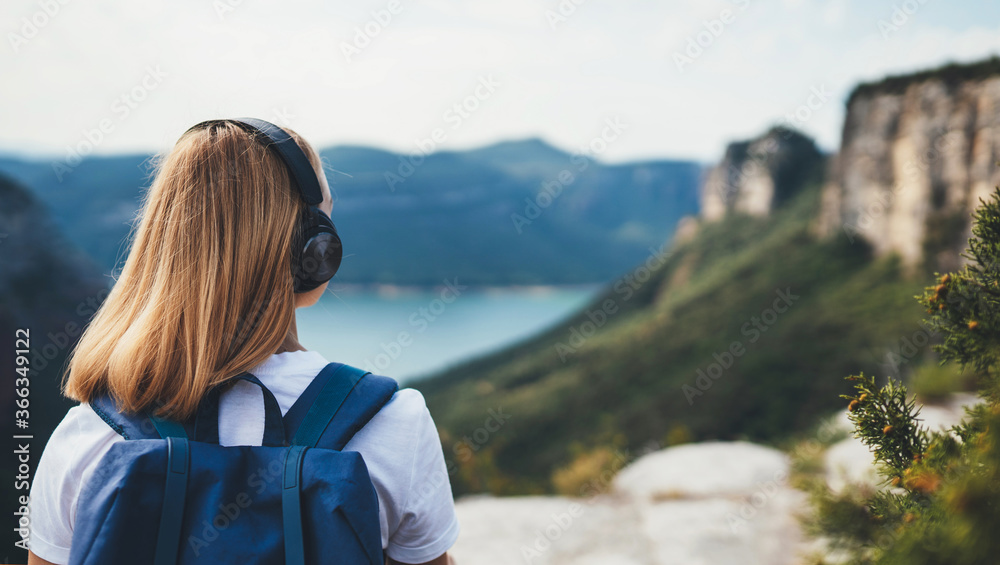 blonde woman meditating listening to music with headphones looking view landscape top of mountain, female tourist with long blond hair leisure after walk hiking and enjoy vacation trip, copy space