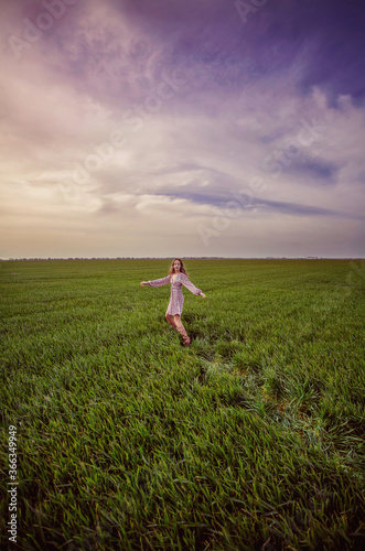  A girl runs across a green field in spring