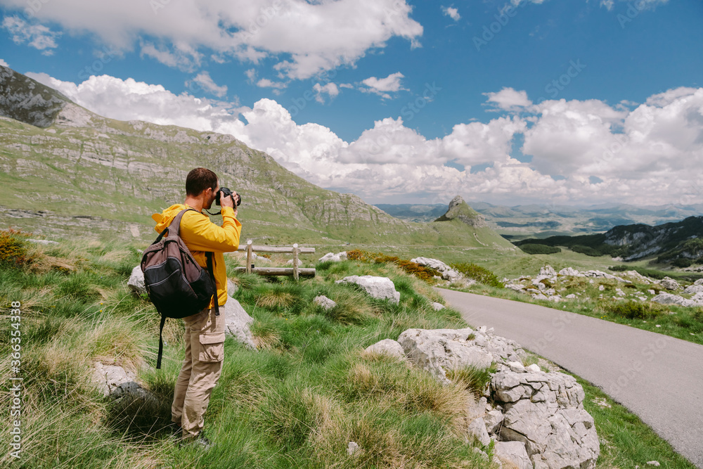 travel photographer in mountains. Professional photographer travel in countryside with camera and taking photos. tourist male with backpack on summer vacations. Montenegro, Durmitor. 